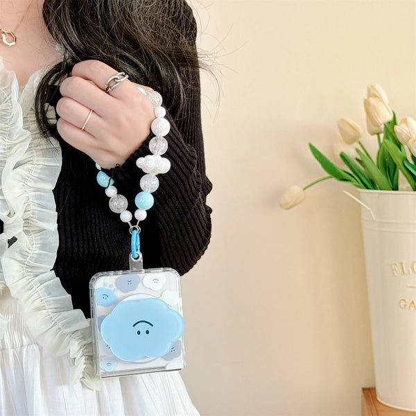 Close-up of a cute cloud phone case with a beaded strap in pastel colors, held by a woman