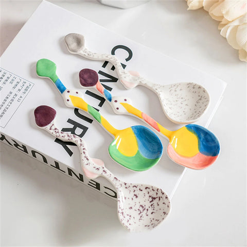 Set of colorful ceramic spoons with unique, artistic designs arranged on a book