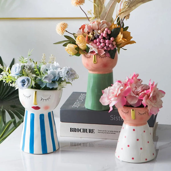 Handmade ceramic doll face vases with floral arrangements