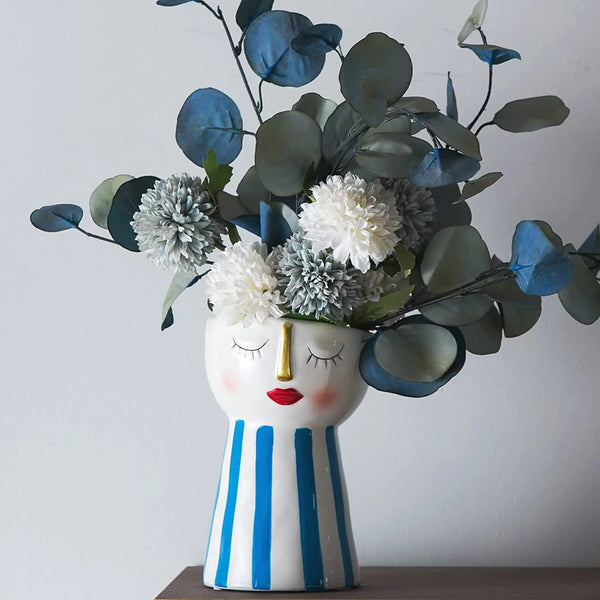 Handmade ceramic doll face vases with floral arrangements